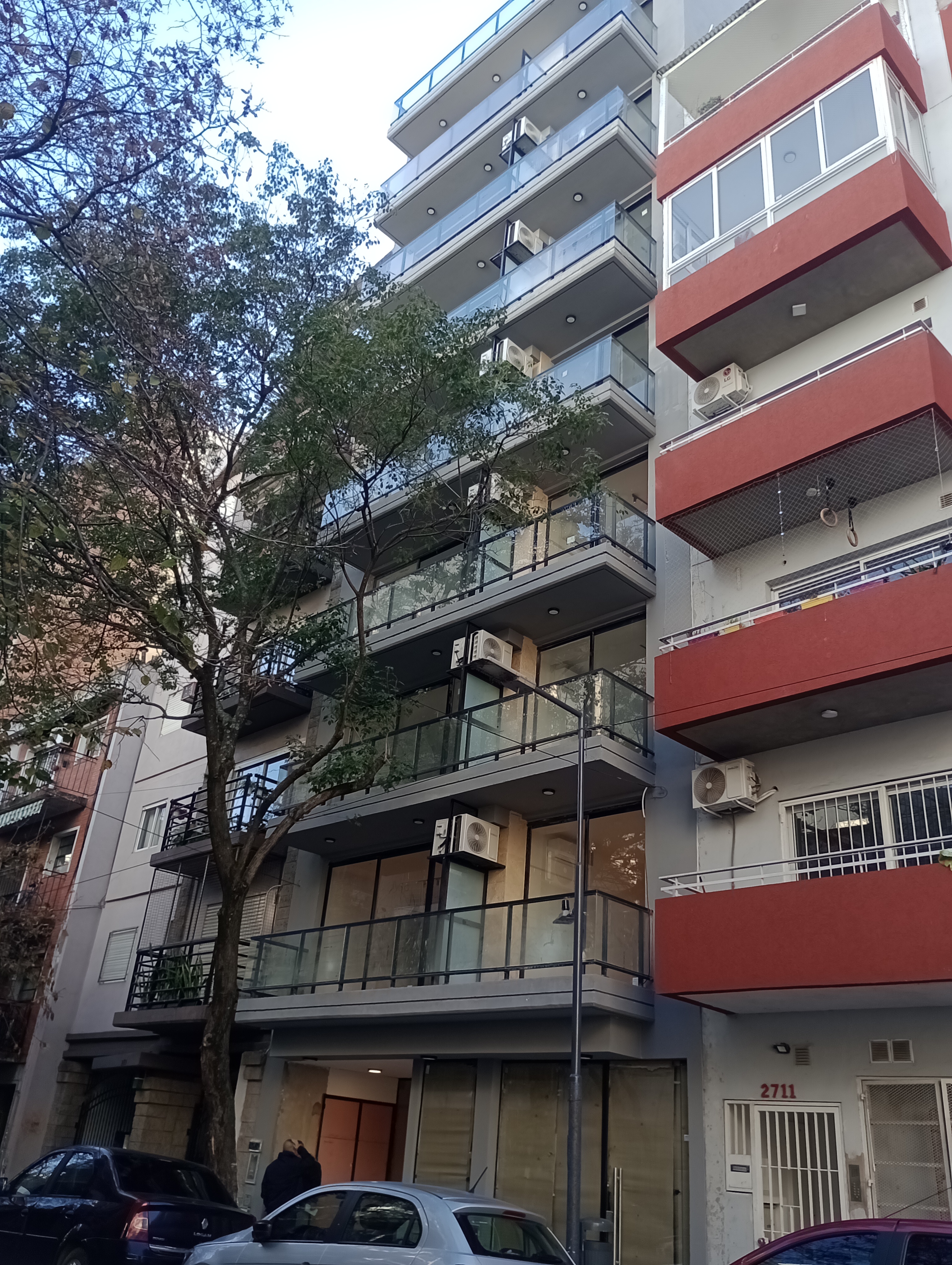 Edificio residencial con balcones de vidrio y unidades de aire acondicionado, GBA